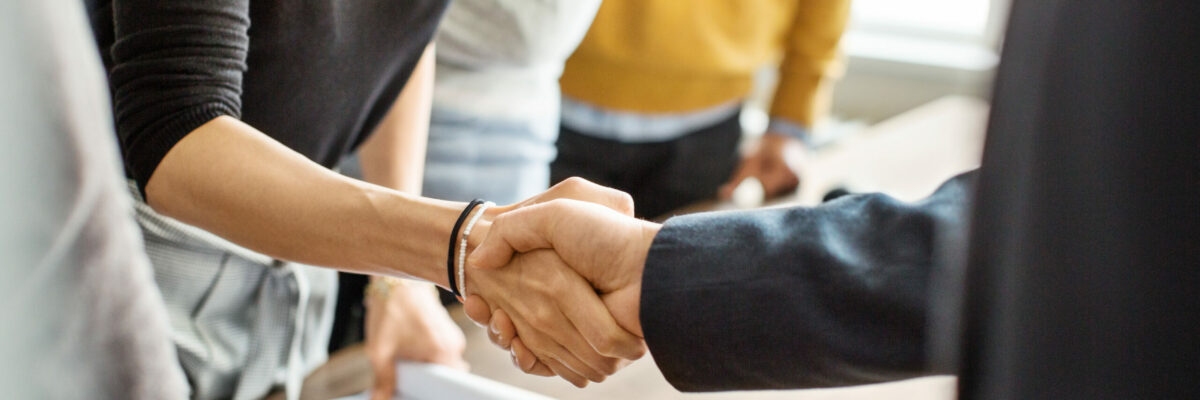 Cropped shot of businessman greeting a young professional around the table in office. Close up of business people shaking hands in office.